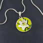 Lily Birth Flower May Graphic Epoxy Disc Necklace. Clear shiny epoxy shows a white petal flower with green stem on a lime green background. The jewellery is made of high quality surgical steel or with an 18k gold finish option with an option to engrave a short love you message or special date. Luxury Necklace: 18-22" (45-56cm) adjustable
Circle Pendant: 0.9” x 0.9” (23.5mm x 23.5mm)