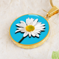 Daisy Birth Flower April Graphic Epoxy Disc Necklace. Clear shiny epoxy shows a white petal flower with yellow canter on a light blue background. The jewellery is made of high quality surgical steel or with an 18k gold finish option with an option to engrave a short love you message or special date. Luxury Necklace: 18-22" (45-56cm) adjustable
Circle Pendant: 0.9” x 0.9” (23.5mm x 23.5mm)